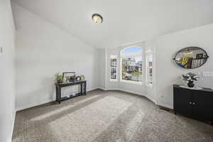 Carpeted spare room with lofted ceiling and baseboards