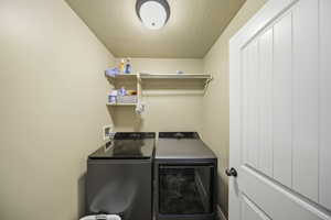 Laundry area with a textured ceiling and washer and dryer