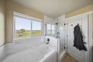 Full bathroom featuring a jetted tub and a marble finish shower