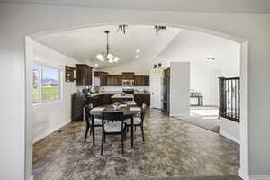 Dining room featuring lofted ceiling, arched walkways, a chandelier, dark tile patterned flooring, and recessed lighting