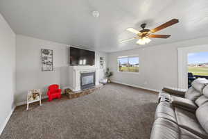 Living area featuring carpet floors, a textured ceiling, a high end fireplace, and ceiling fan