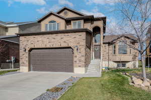 View of front of home with concrete driveway, stucco siding, a garage, and a front lawn