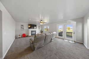 Carpeted living area with a glass covered fireplace, a textured ceiling, and ceiling fan