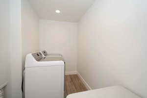 Laundry area featuring light wood finished floors, washer and dryer, and recessed lighting