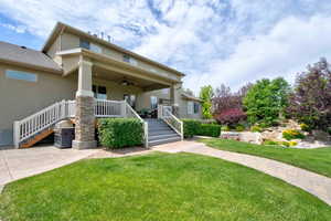 View of front of home with ceiling fan, a front yard, stucco siding, stairway, and a porch