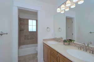 Full bathroom featuring double vanity, light tile patterned floors, and shower / bathtub combination