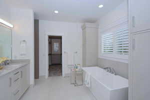Bathroom with a soaking tub, healthy amount of natural light, recessed lighting, vanity, and light tile patterned flooring