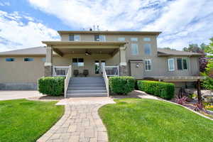 View of front of property featuring ceiling fan, stucco siding, covered porch, and a front lawn