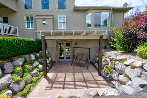 Rear view of house with stucco siding, a patio, and french doors