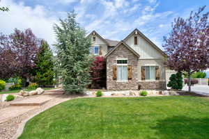 Craftsman-style home featuring stone siding, board and batten siding, a front lawn, and an attached garage