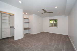 Unfurnished bedroom featuring dark colored carpet, recessed lighting, built in desk, a closet, and a ceiling fan