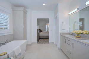 Ensuite bathroom with double vanity, a freestanding bath, recessed lighting, and light tile patterned floors
