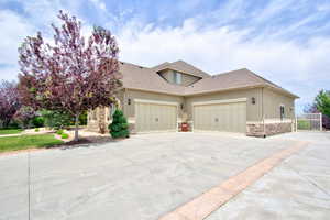 View of front of property featuring stone siding, driveway, stucco siding, a garage, and a shingled roof