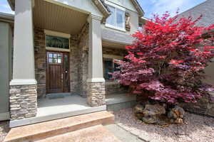 Entrance to property featuring stone siding and a porch