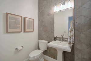 Half bathroom featuring toilet and tile walls