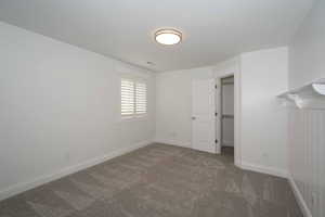 Unfurnished bedroom with dark carpet and a spacious closet
