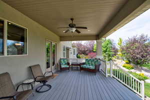 Wooden porch featuring ceiling fan and an outdoor hangout area