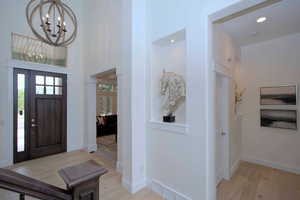 Foyer entrance with light wood-type flooring, a chandelier, and a towering ceiling