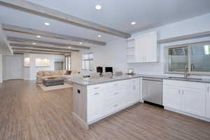 Kitchen with white cabinetry, beamed ceiling, open shelves, light stone countertops, and decorative backsplash