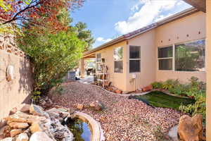 View of side of property with a patio area, a fenced backyard, stucco siding, and a garden pond