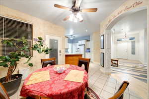 Dining area with ceiling fan, light tile patterned flooring, and arched walkways