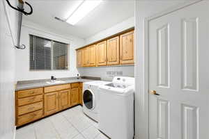 Laundry area with light tile patterned floors, cabinet space, and independent washer and dryer