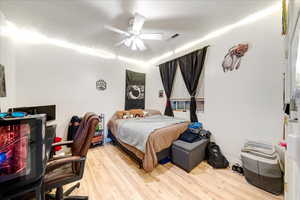 Bedroom featuring light wood-style flooring, a ceiling fan, and a desk