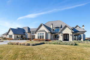 French country style house with stone siding, a front yard, a standing seam roof, and a chimney