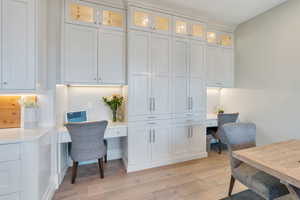 Office with built in desk and light wood-style flooring