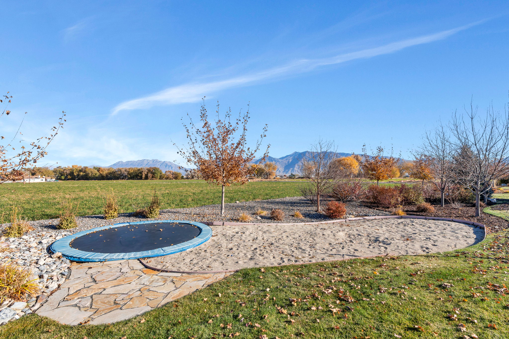 View of grassy yard with a trampoline and a mountain view