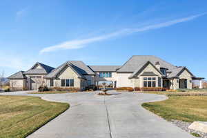 French provincial home featuring stone siding, a front lawn, and curved driveway