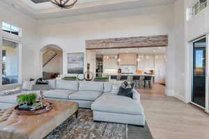 Living area featuring a towering ceiling, light wood-type flooring, stairway, a chandelier, and recessed lighting