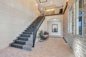 Staircase with high vaulted ceiling, recessed lighting, and arched walkways