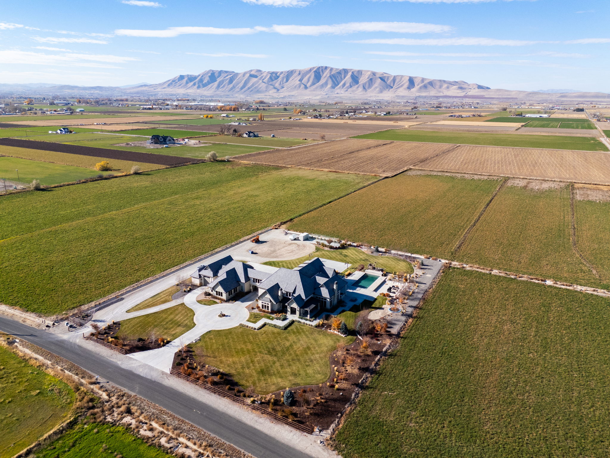 Aerial view of sparsely populated area featuring a mountain backdrop and rows of crops