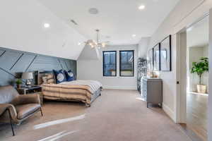 Bedroom featuring vaulted ceiling, recessed lighting, light carpet, and a decorative wall