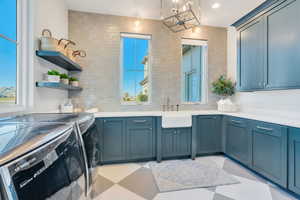 Laundry room featuring tasteful backsplash, washing machine and dryer, a chandelier, and light floors