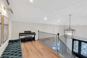 Corridor featuring recessed lighting, light wood-style flooring, a chandelier, and an upstairs landing
