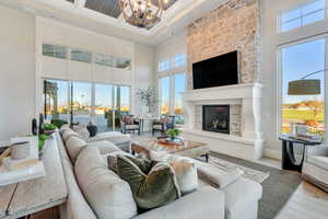 Living area featuring wood finished floors, a chandelier, a large fireplace, a towering ceiling, and coffered ceiling