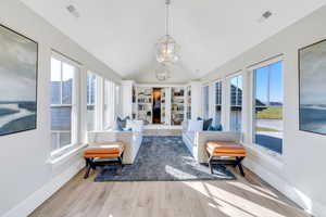 Sunroom / solarium featuring lofted ceiling, healthy amount of natural light, and a chandelier