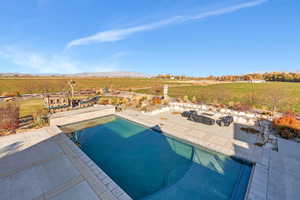 Swimming pool featuring a patio area, a view of rural / pastoral area, and a mountain view