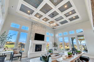 Living area with beamed ceiling, coffered ceiling, a towering ceiling, wood finished floors, and a fireplace