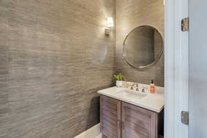 Half bath featuring vanity and wallpapered walls