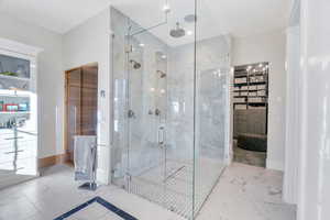 Full bath with marble look tile flooring and a marble finish shower