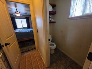 Ensuite bathroom with dark tile patterned floors and ceiling fan