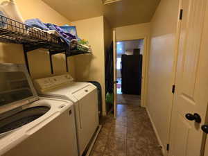 Laundry area with washer and dryer and dark tile patterned floors