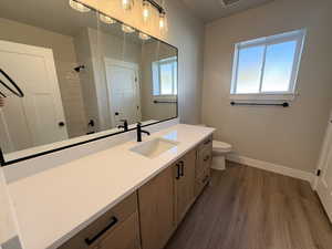 Bathroom featuring vanity, dark wood-style flooring, and a tile shower