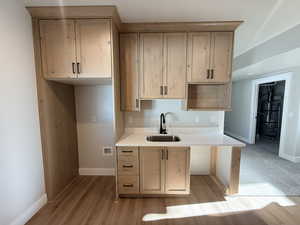 Kitchen featuring light wood-type flooring, light stone countertops, and light brown cabinetry