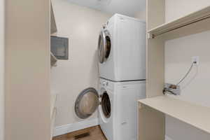 Washroom featuring stacked washer and clothes dryer, tile patterned floors, and electric panel