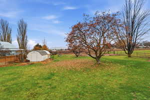 Fenced backyard featuring a storage unit