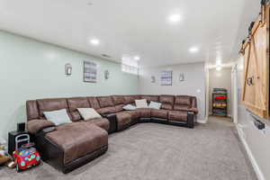 Living area with a barn door, carpet flooring, and recessed lighting